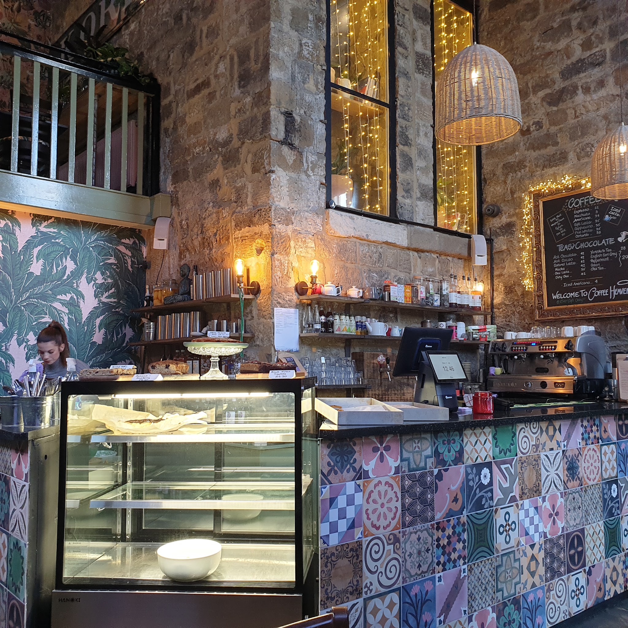 The cafe counter with patterned tiles, exposed stone and warm pendant lights