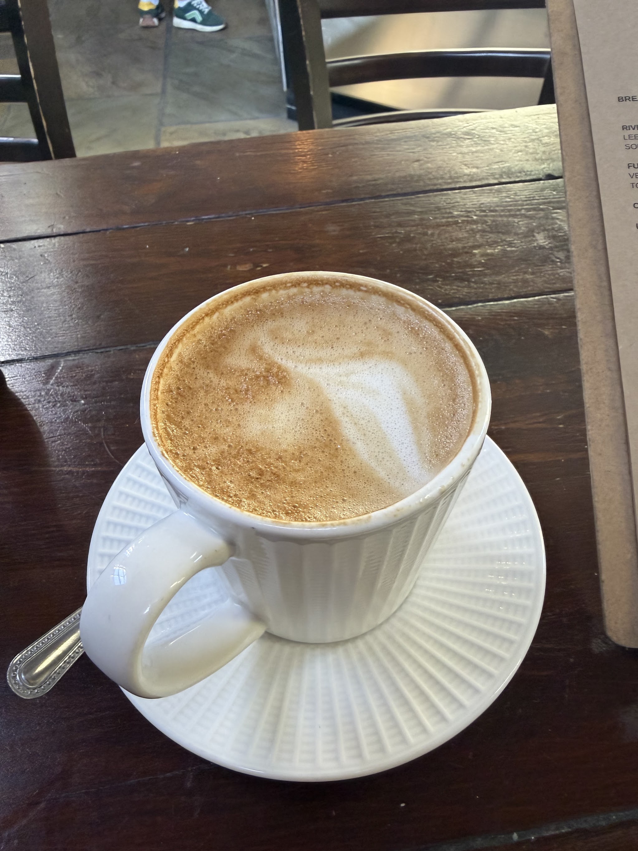 A freshly made coffee in a white cup on a wooden table